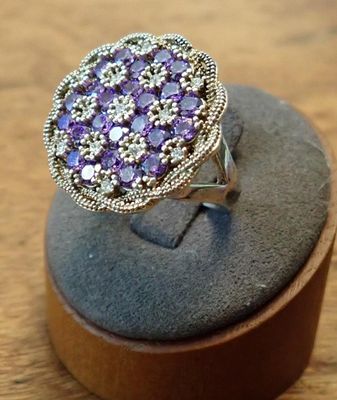 silver ring with amethoralite and diamonds on display on wooden stand