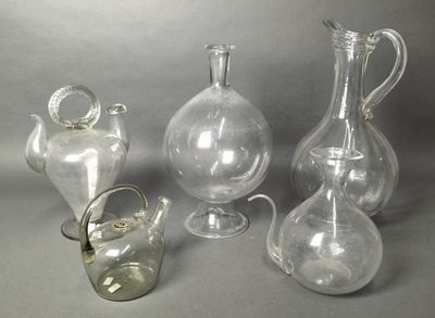 three clear glass vases and a glass pitcher on a gray background