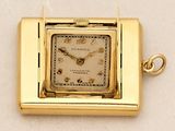 a small square gold watch with a chain around it