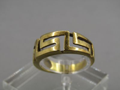 un gros plan d'une bague en or posée sur une surface transparente