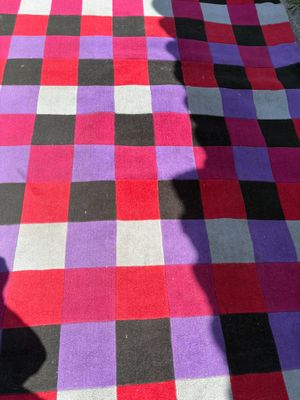 purple and black checkered rug on the ground with a shadow of a person on it