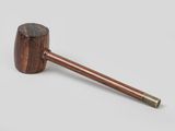 an old pipe with a wooden handle sitting on top of a white surface