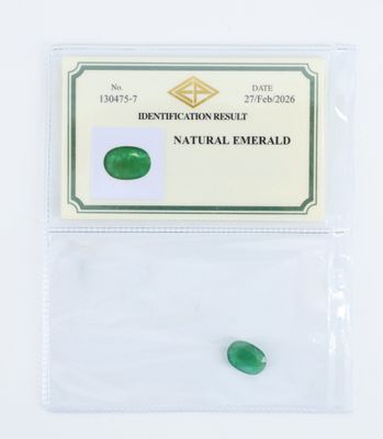 des pierres précieuses vert émeraude dans un sachet transparent posé sur une surface blanche