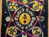 a black square scarf with gold and black designs on it
