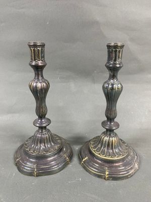 paire de bougeoirs anciens en argent sur un socle, sur fond gris