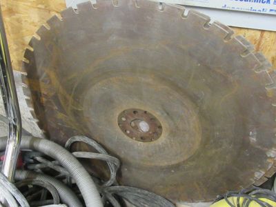 une photo montrant une grande lame de scie posée sur une pile d'autres outils