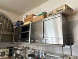 des placards en acier inoxydable dans une cuisine, sur lesquels sont posées des casseroles et des poêles