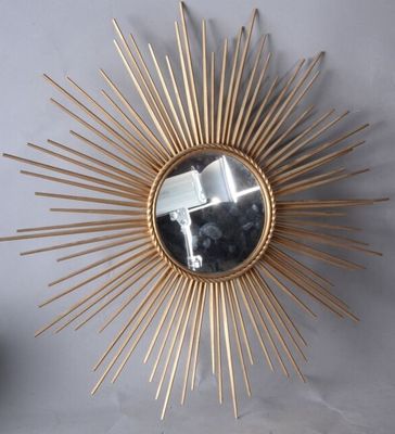 un miroir doré en forme d'étoile accroché au mur à côté d'un vase