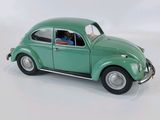 a green toy car that is sitting on a white surface