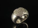 a close up of a silver ring with diamonds on a black surface