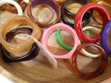 a wooden bowl filled with lots of different colored bangles