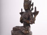 bronze statue of a woman sitting on a rock with a bird in her hand