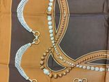 brown and white square scarf with tassels and beads on it