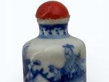 a small blue and white vase with a red lid