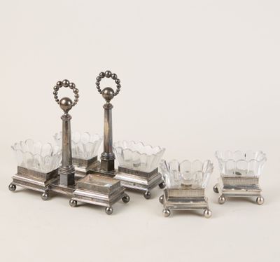 trois bougeoirs en métal argenté et quatre verres posés sur un support