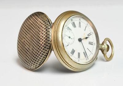 a gold pocket watch with roman numerals on it