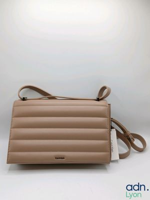 un sac à main en cuir beige muni d'une bandoulière et d'une étiquette blanche