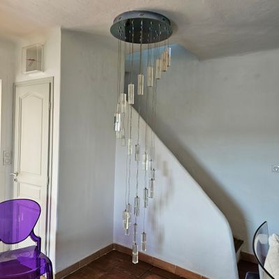 une chaise violette dans un coin d'une pièce où un lustre est suspendu au plafond