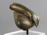 sculpture en bronze représentant une main tenant un oiseau, posée sur un socle transparent
