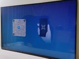 a large flat screen tv on the wall with a hand holding a remote control
