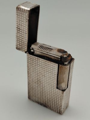 un vieux briquet en argent posé sur une surface blanche