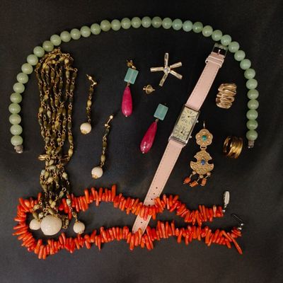 un collier, un bracelet, une montre et d'autres bijoux disposés sur une surface noire