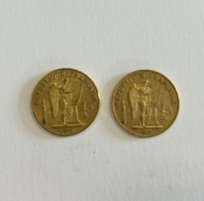 two gold coins sitting on top of each other on a white surface