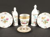 cinq pièces de vaisselle en porcelaine posées sur une table, accompagnées d'une tasse et d'une soucoupe