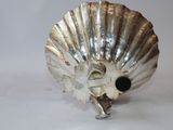 a silver shell shaped object on a white surface