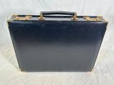 an old black suitcase sitting on top of a white surface