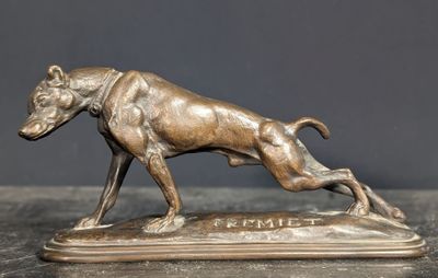 statue en bronze représentant un chien en train de courir, posée sur un socle posé sur une table