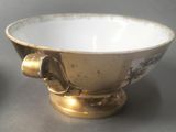 a gold bowl with a handle on a table