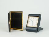 une petite horloge posée à côté d'une autre petite horloge sur une table