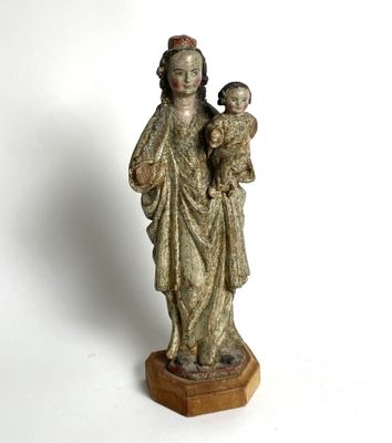 an old statue of a woman holding a child on a wooden base