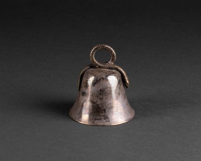 a silver bell with a snake on top of it on a black background