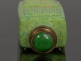 a small green bottle with a green stone on it