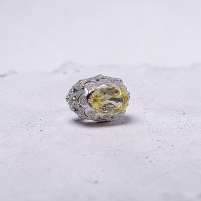 une photo d'une bague sertie d'un diamant jaune posée sur une surface blanche