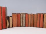 several old books stacked on top of each other on a white surface