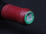 a close up of a bottle of wine with a green cap