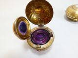 un cadenas doré renfermant un verre violet