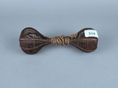 un nœud papillon en osier marron muni d'une étiquette, sur fond gris