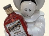 a ceramic figurine of a chef holding a bottle of bourbon