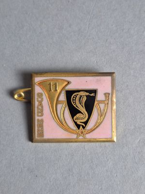 un gros plan sur un insigne doré et rose orné d'un serpent