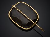 a gold plated broochle with black glass and a long stick