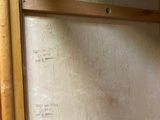 a toilet in the corner of a room with a wooden shelf