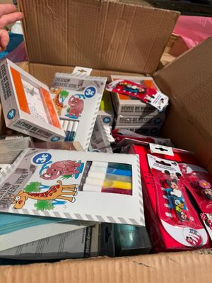 a cardboard box filled with assorted items and a child ' s hand holding a pair of scissors