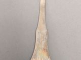 an old silver spoon with a long handle on a gray surface