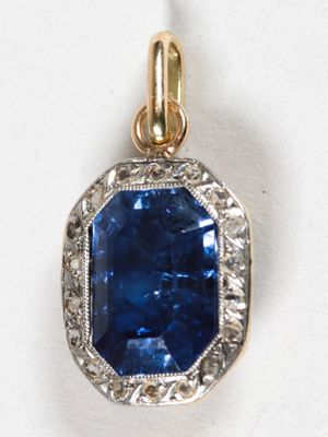 un gros plan d'un pendentif en saphir bleu et diamants sur une surface blanche