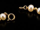 a pair of gold and pearl earrings on a black background