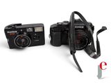 two cameras sitting next to each other on a white surface